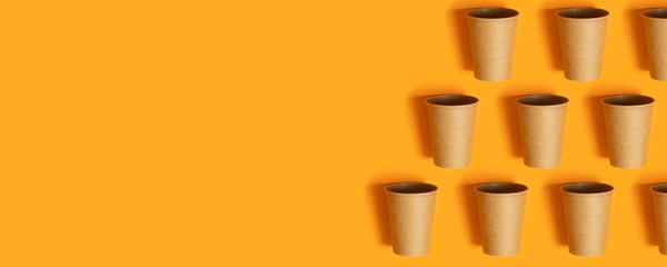 Coffee paper cup pattern in minimalistic style on an orange background. Creative concept. Copy space.