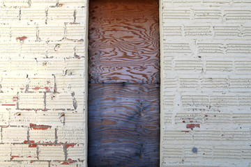 faded whitewashed block building wall boarded up wood door