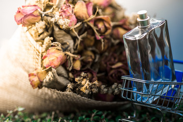 background view of a clear bottle containing perfume placed near a bouquet of roses on the table, business concept selling products or cosmetic products