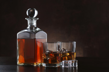 Bottle of whiskey with glasses on brown background