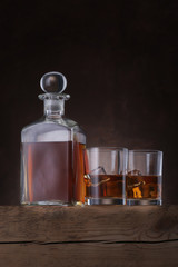 Bottle of whiskey with glasses on brown background