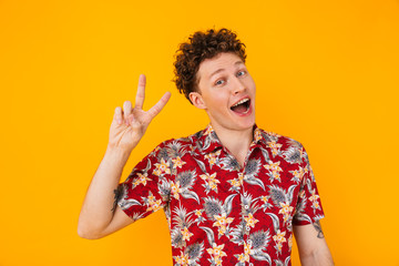 Image of caucasian delighted man smiling and gesturing peace sign