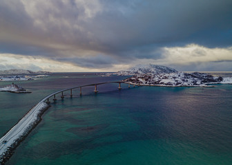 drone view of Sommaroy bridge in Norway and the snowstorm in the distance which clouded the sky and the transparent turquoise water