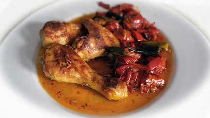 a grilled chicken with red paprika and cherry tomatoes in sauce