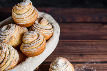 Modern trend baking in 2020-cruffins, puffmuffin, a mixture of croissants and muffins. On a dark wooden table sprinkled with powdered sugar. the view from the top. close up