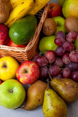 Fruit basket with place for text. Set of different fruits on a wooden kitchen table. Vitamin nutrition, healthy food. Red grapes, blueberries, mangoes, orange, apple, kiwi.