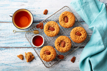 Pecan nut muffins on cooling rack with a cup of tea. Blue wooden background. Top view.