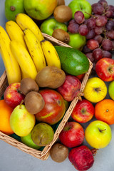 Fruit basket with place for text. Set of different fruits on a wooden kitchen table. Vitamin nutrition, healthy food. Red grapes, blueberries, mangoes, orange, apple, kiwi.