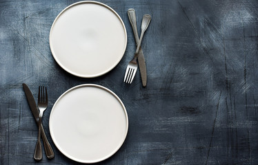 White craft plate, cutlery and napkin on dark stone table. Top view, copy space, Table setting....