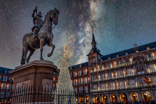 Madrid, bronze statue of King Philip III against a starry night sky and illuminated christmas tree in Plaza Mayor.