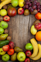 Fruit background with place for text. Different fruits assorted on a wooden table. Vitamin food. Apples, pears, bananas, oranges, kiwi, mango, avocado. A set of healthy food. Frame of fruits. 