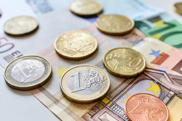 Calculation of expenses. Close up of one euro coin surrounded by different coins and 100 and 50 Euro banknotes