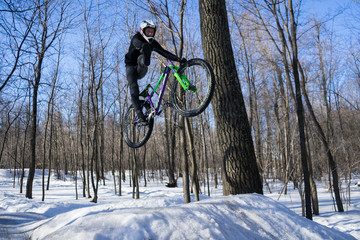 Mountainbike rider cycling in winter dirt jumping. An athlete in a helmet does a trick on a bicycle...