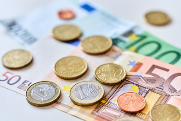 Calculation of expenses. Close up of one euro coin surrounded by different coins and 100 and 50 Euro banknotes