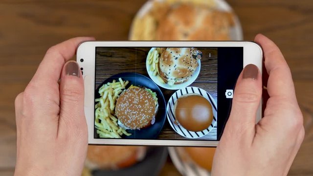 A Woman's Hands Take photos of Fast Food Burgers and Fries on a Smartphone
