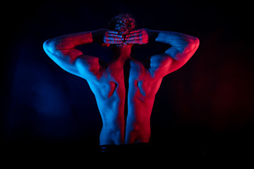 Obraz premium Male wrestler posing . studio black-white background, red and blue lights.