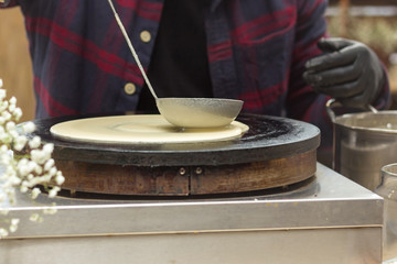 Close-up soup ladle with dough and oven. The dough is pouring on a crepe maker. A series of photos. Step-by-step photo recipe for pancakes.