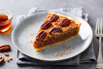 Pecan pie slice on a plate. Grey background. Close up.