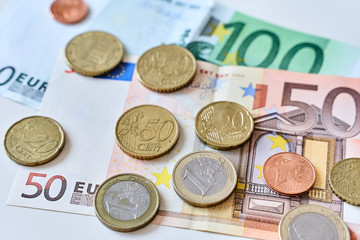 Calculation of expenses. Close up of one euro coin surrounded by different coins and 100 and 50 Euro banknotes