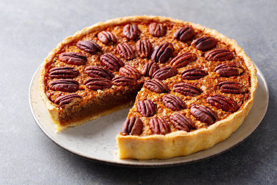Pecan nut pie, tart on a plate. Grey background. Close up.