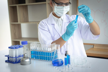 Scientists are carrying blue chemical test tubes to prepare for the determination of chemical composition and biological mass in a scientific laboratory, Scientists and research in the lab Concept.