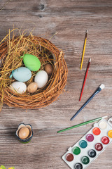 easter nest with eggs, paints and brushes