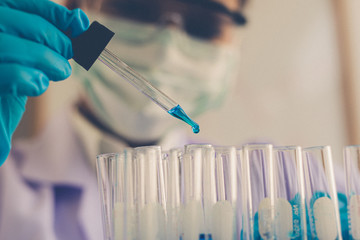 Scientists are carrying blue chemical test tubes to prepare for the determination of chemical composition and biological mass in a scientific laboratory, Scientists and research in the lab Concept.