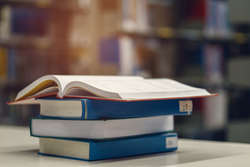 Open book on stack of books in library at school, university, college.
