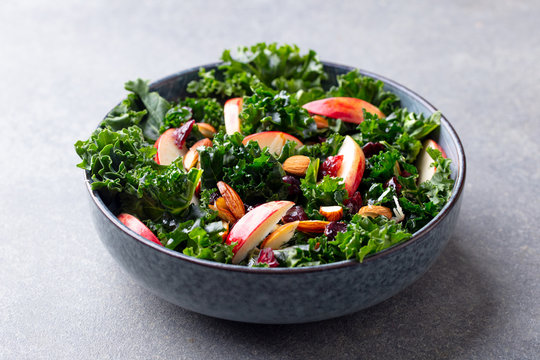 Kale salad with apples and nuts. Grey background. Close up.