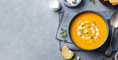 Pumpkin, carrot cream soup in a bowl. Grey background. Top view. Copy space. - 327868845