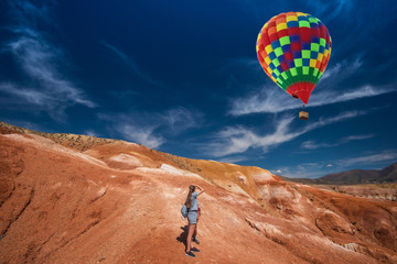 Woman with her son in valley of Mars landscapes in the Altai Mountains, Kyzyl Chin, Siberia, Russia, Aerostat in the sky.