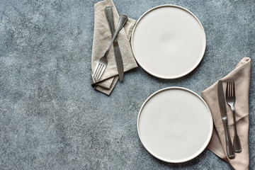 White craft plate, cutlery and napkin on dark stone table. Top view, copy space, Table setting....