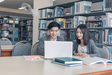 High school or college students studying and reading together in library. Student use laptop at library.