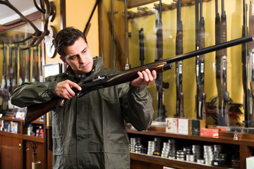 Portrait of young confident man showing rifle