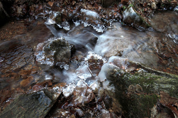 Lód na zamarzniętym górskim potoku płynie szybko nurt rwący skaliste dno © Maciek