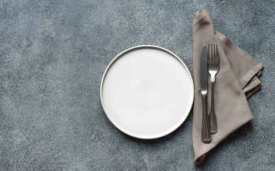 White craft plate, cutlery and napkin on dark stone table. Top view, copy space, Table setting....