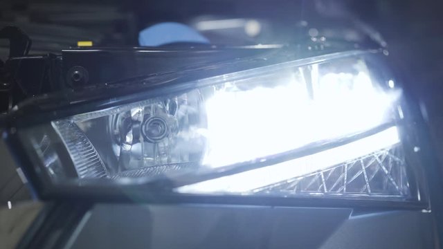 Close-up of car headlight turning on and off. Car dealership, auto repair shop, automotive industry.