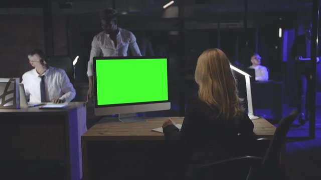 Woman manager working on desktop computer in dark office