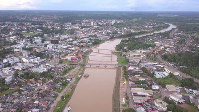 Panoramic aerial drone view of Acre river in the amazon. Rio Branco city center buildings, houses, streets, bridges on cloudy day. Brazil. Concept of environment, ecology, climate change and travel.
