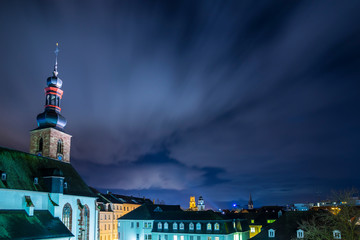 Germany, Magical night sky over roofs and skyline of saarbruecken city at schlosskirche church by...