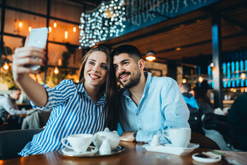 man and woman couple using mobile phone in cafeteria