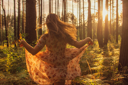 Portrait of young beautiful girl in summer dress in forest that dancing