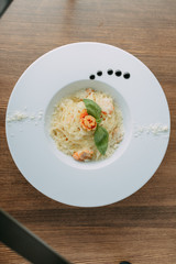 Italian pasta fettuccine in a creamy sauce with shrimp on a plate, top view