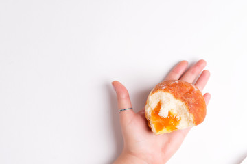 Homemade fresh doughnut with apricot jam in a woman hand above white background