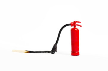 Miniature fire extinguisher close to a burnt match against a white background, macro shot