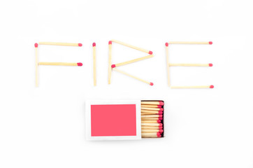Text fire made of matches including a rose matchbox on white
