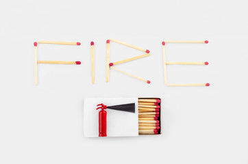 Word fire made of matches including matchbox and a tiny fire extinguisher