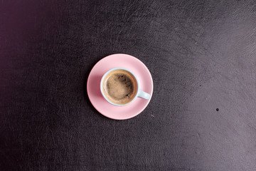 Freshly brewed aromatic coffee drink on a background from decorative black artificial eco leather. Top view.