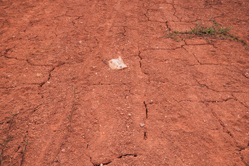 Dry cracked red soil texture in rural Indonesia, pictured on a warm day in Padang, West Sumatra.