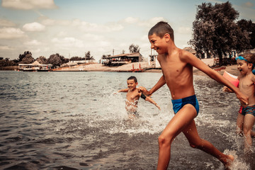 Happy boys running through the water and having fun in summer day.